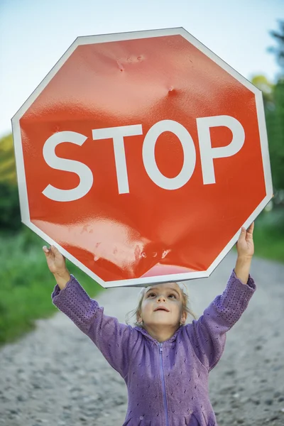 Kleines Mädchen mit rotem Schild "Stop" — Stockfoto