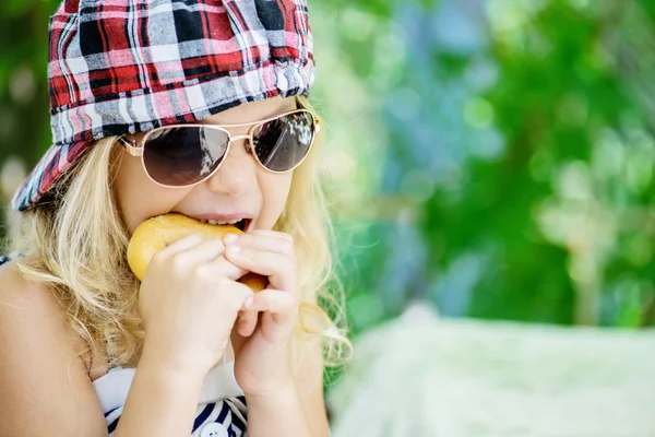 Petite fille parlant en bonnet à carreaux et lunettes de soleil — Photo