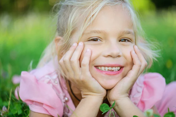Bela menina sorridente encontra-se na grama verde — Fotografia de Stock
