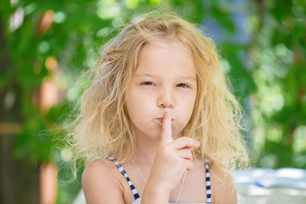 Cheerful girl puts index finger to lips — Stock Photo, Image