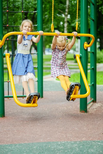 Twee meisjes swingen op speelplaats — Stockfoto