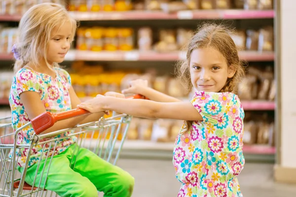 Pequeñas hermanas hermosas en el supermercado — Foto de Stock