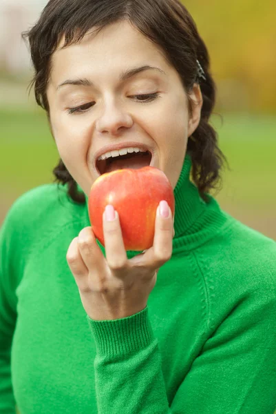 Menina morde uma maçã — Fotografia de Stock