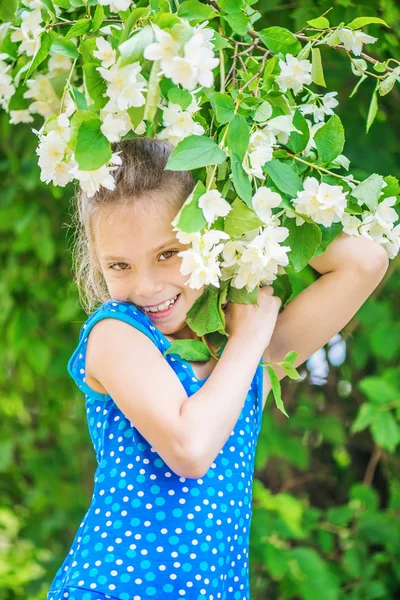 Ragazza sorridente vicino gelsomino in fiore — Foto Stock