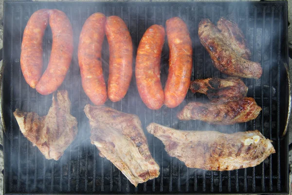 Varkensribbetjes en worsten op de grill — Stockfoto