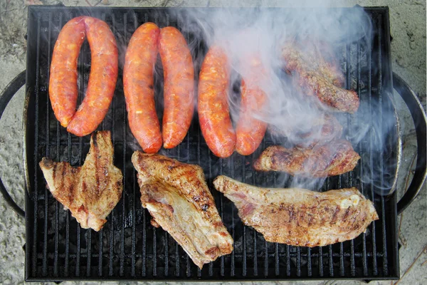 Varkensribbetjes en worsten op de grill — Stockfoto