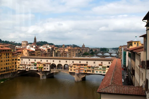 Multitud de turistas visitan el Ponte Vecchio ("Puente Viejo") que es un puente medieval sobre el río Arno en Florencia, Toscana, Italia . — Foto de Stock