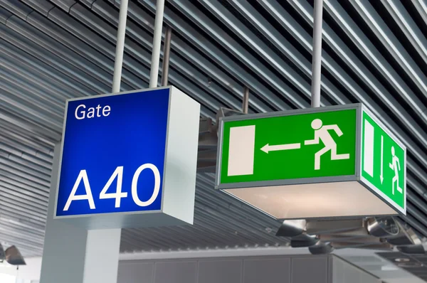 Panneau de sortie d'urgence vert, et panneau de porte bleue à l'aéroport — Photo