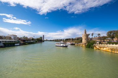 SEVILLE, SPAIN - 06 Nisan 2019: Guadalkivir nehri ve Torre del Oro, İspanya 'nın büyük bir turizm merkezi olan Seville' deki tarihi kireçtaşı kulesi