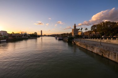 SEVILLE, SPAIN - 06 Nisan 2019: Guadalkivir nehri ve Torre del Oro, İspanya 'nın büyük bir turizm merkezi olan Seville' deki tarihi kireçtaşı kulesi