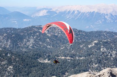 KEMER, TURKEY - 22 Ekim 2017: Türkiye 'nin Antalya ilindeki Türk Rivierası' nda bir sahil beldesi olan Kemer yakınlarındaki dağların üzerinden uçan paraglider