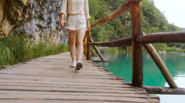 Plitvice Gölleri 'nde tahta patika boyunca yürüyen genç bir kadın.