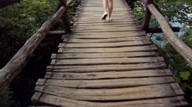 Plitvice Ulusal Parkı 'nda tahta köprü boyunca yürüyen şortlu genç kız.