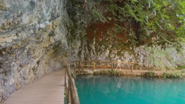 Göl boyunca tahta bir patika boyunca yürüyen şapkalı çekici bir turist. Plitvice Gölleri, Hırvatistan
