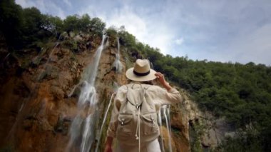 Dağdaki şelalenin şelalesinde çekici bir gezgin.