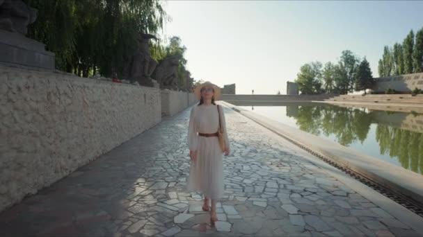 Привлекательная женщина, прогуливающаяся у пруда у мемориального комплекса — стоковое видео
