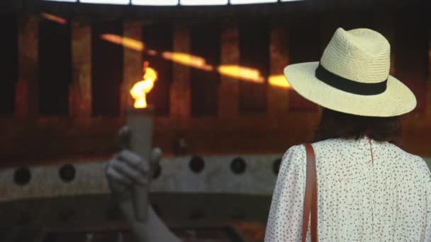 Mladá dívka v klobouku dívá se na věčný plamen v panteonu — Stock video