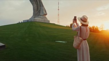 Anavatanın fotoğrafını çeken genç bir turist akıllı bir telefonla Mamayev Kurgan 'da.