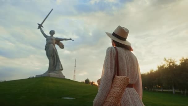 傍晚时分，一个穿着连衣裙的漂亮女人在Mamayev Kurgan山上望着母亲的祖国 — 图库视频影像
