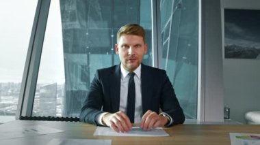 Takım elbiseli yetişkin bir işadamı video aracılığıyla iletişim kuruyor. İş adamı internette iş arkadaşını dinliyor.