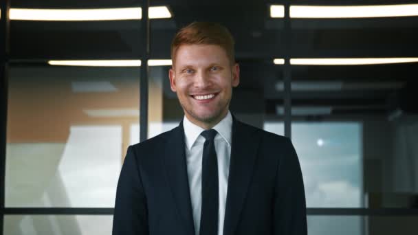 Улыбающийся человек в костюме в офисе. Бизнесмен смотрит в камеру. Портрет с видом на лицо — стоковое видео