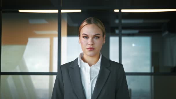 Улыбающаяся женщина в костюме в офисе. Бизнесмен смотрит в камеру. Портрет с видом на лицо — стоковое видео