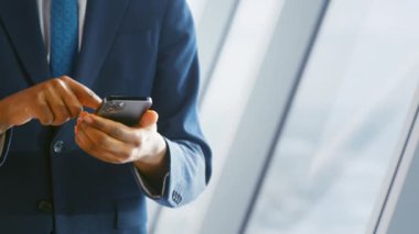 Ofiste akıllı telefon kullanan takım elbiseli genç bir adam. İş konsepti kapat