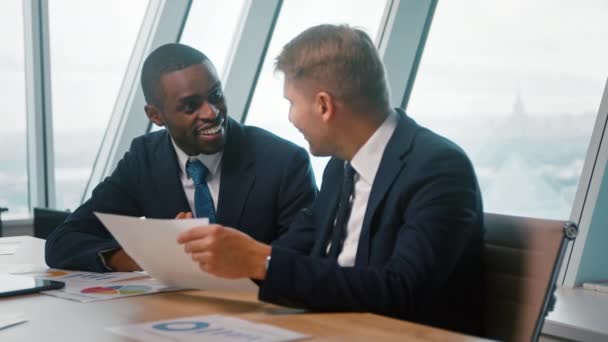 Lächelnde männliche Kollegen diskutieren im Büro über ein neues Projekt. Geschäftsleute bei einem Meeting — Stockvideo