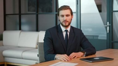 Takım elbiseli genç adam ofiste video görüşmeleri yapıyor.