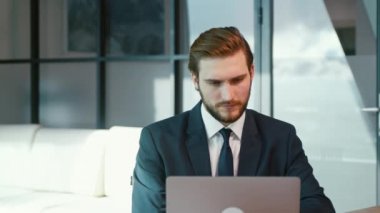 Genç adam internette dizüstü bilgisayar kullanarak sörf yapıyor. Dizüstü bilgisayarı olan bir iş adamı