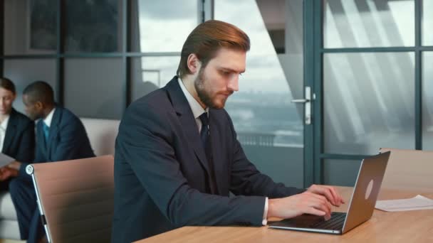 Werkende man in een pak met een laptop op kantoor. Jonge zakenman aan het werk — Stockvideo