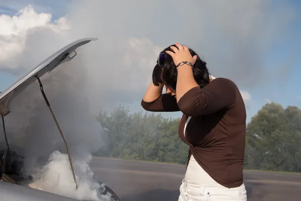 Woman looking at smoking car engine — Stock Photo, Image