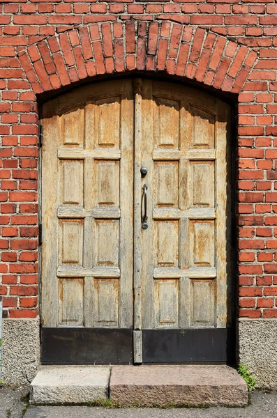 Большая желтая дверь в кирпичной стене — стоковое фото