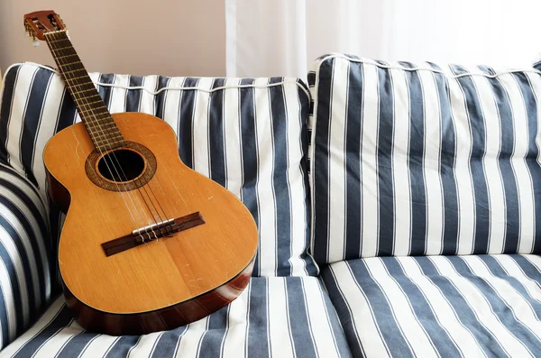 Guitarra acústica em um sofá — Fotografia de Stock