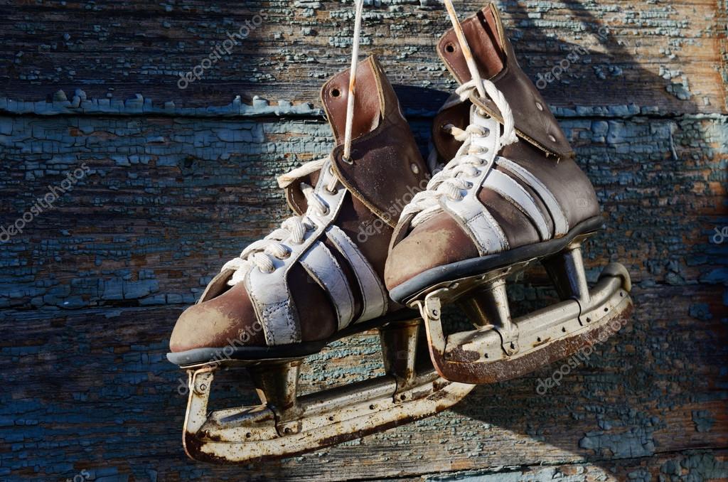 Vintage pair of mens ice skates hanging on a wooden wall with c