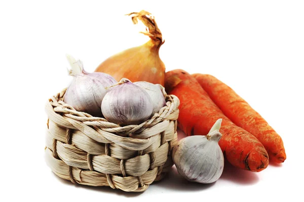 Garlic in a small wicker basket, carrots and onions — Stock Photo, Image