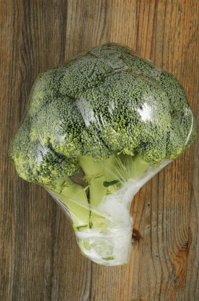 Brocoli chou dans un sac en plastique sur un fond en bois — Photo