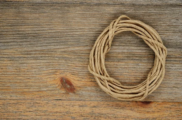 Oval hank of packthread over wooden texture — Stock Photo, Image