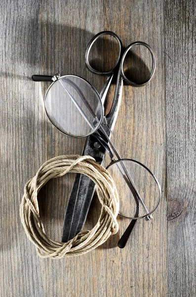 Old scissors, glasses and hank of packthread on wooden backgroun — Stock Photo, Image