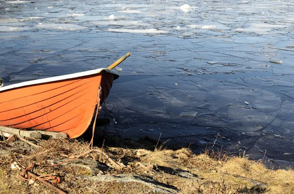 Pomarańczowa łódź ratownicza na brzegu zamarzniętego jeziora — Zdjęcie stockowe