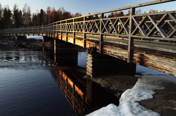 Старый деревянный мост через реку на закате — стоковое фото
