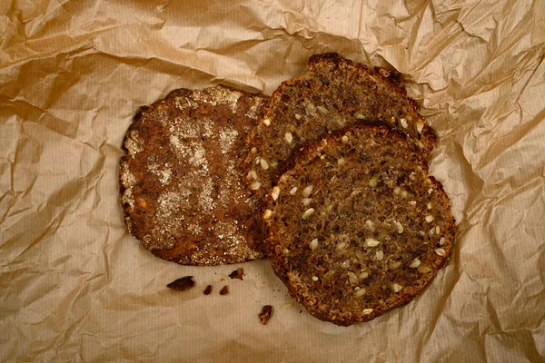 用葵花籽和亚麻籽在皱巴巴的褐色纸片上的黑麦面包 — 图库照片