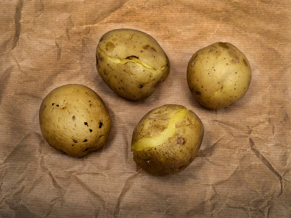 Τέσσερις Βραστές Πατάτες Τραχύ Καφέ Χαρτί — Φωτογραφία Αρχείου