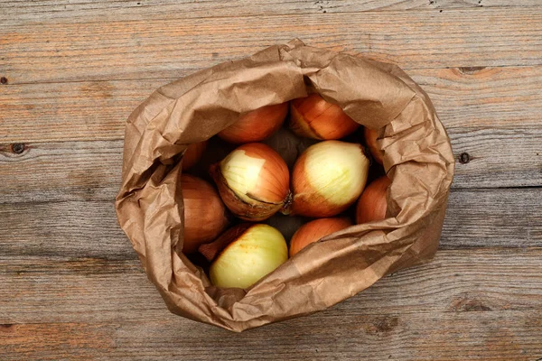 Tahta Bir Masada Kese Kağıdındaki Soğan Soğanları — Stok fotoğraf