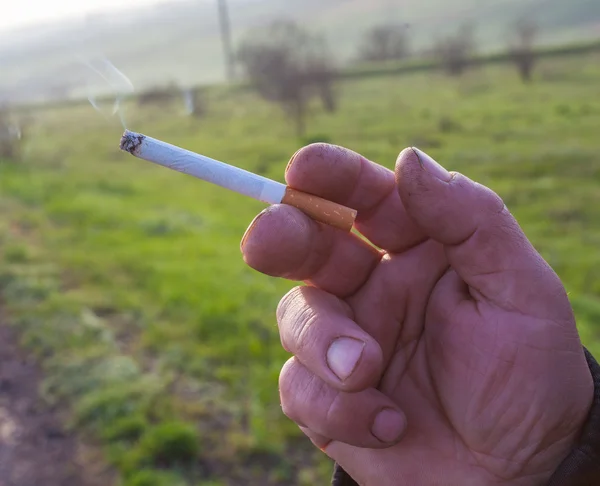 El cigarrillo está en la mano del hombre . — Foto de Stock