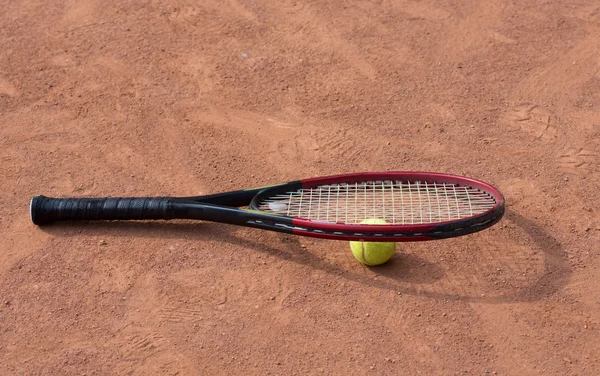 Raqueta de tenis y pelotas en la cancha de barro —  Fotos de Stock