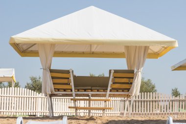 plaj sandalyeleri ve sazdan şemsiye ile