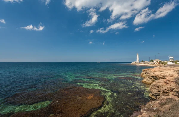 Farol, mar e rocha, céu azul — Fotografia de Stock