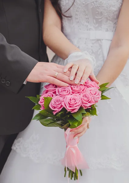 Mãos e anéis no buquê de casamento — Fotografia de Stock