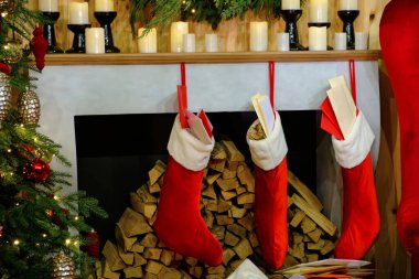 Yılbaşı odasındaki şöminede mumlar, Noel çam dalları Noel çorapları, Noel ağacı ve Noel şöminesi.